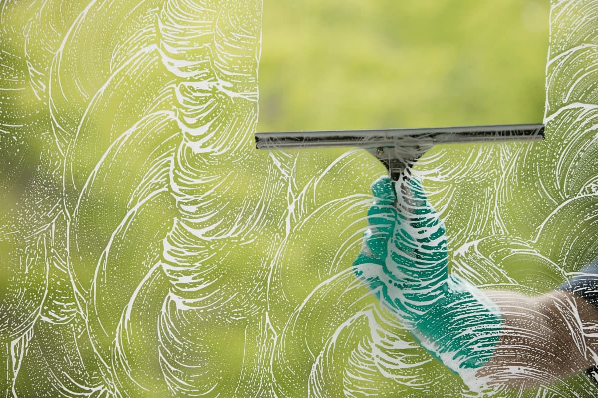 Gloved hand pulling a squeegee across a clean window