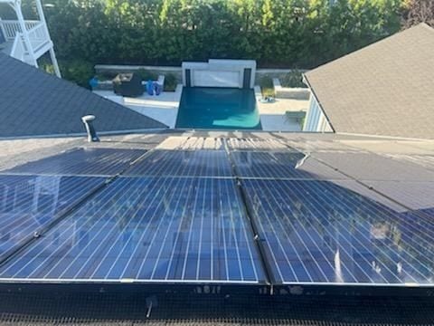 Clean residential solar panel array seen from above next to a pool