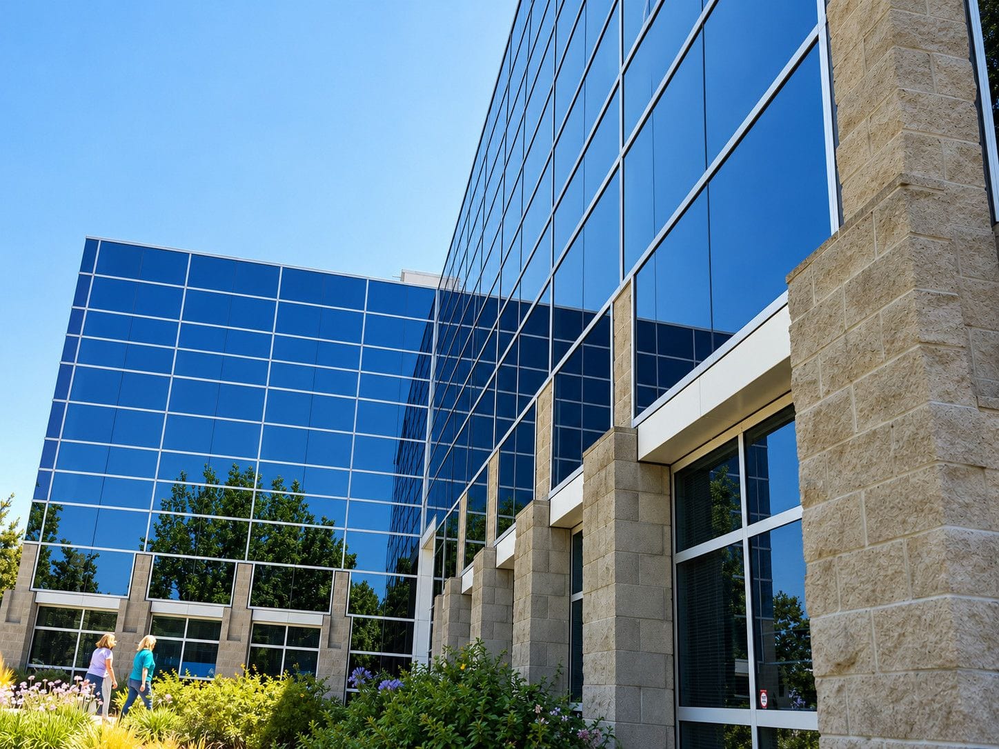 Large glass-fronted commercial building with technicians cleaning the exterior windows