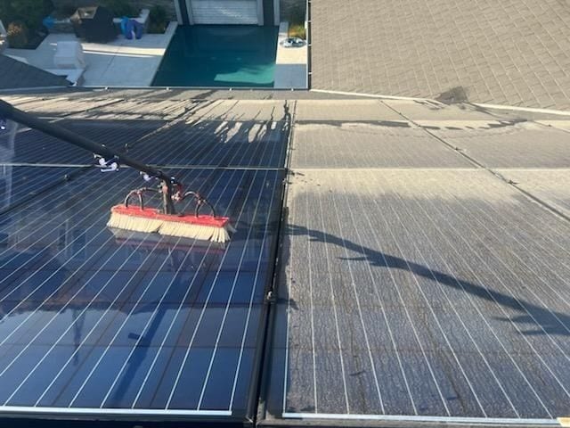 Brush cleaning solar panels, with a cleaned section beside a section not yet cleaned