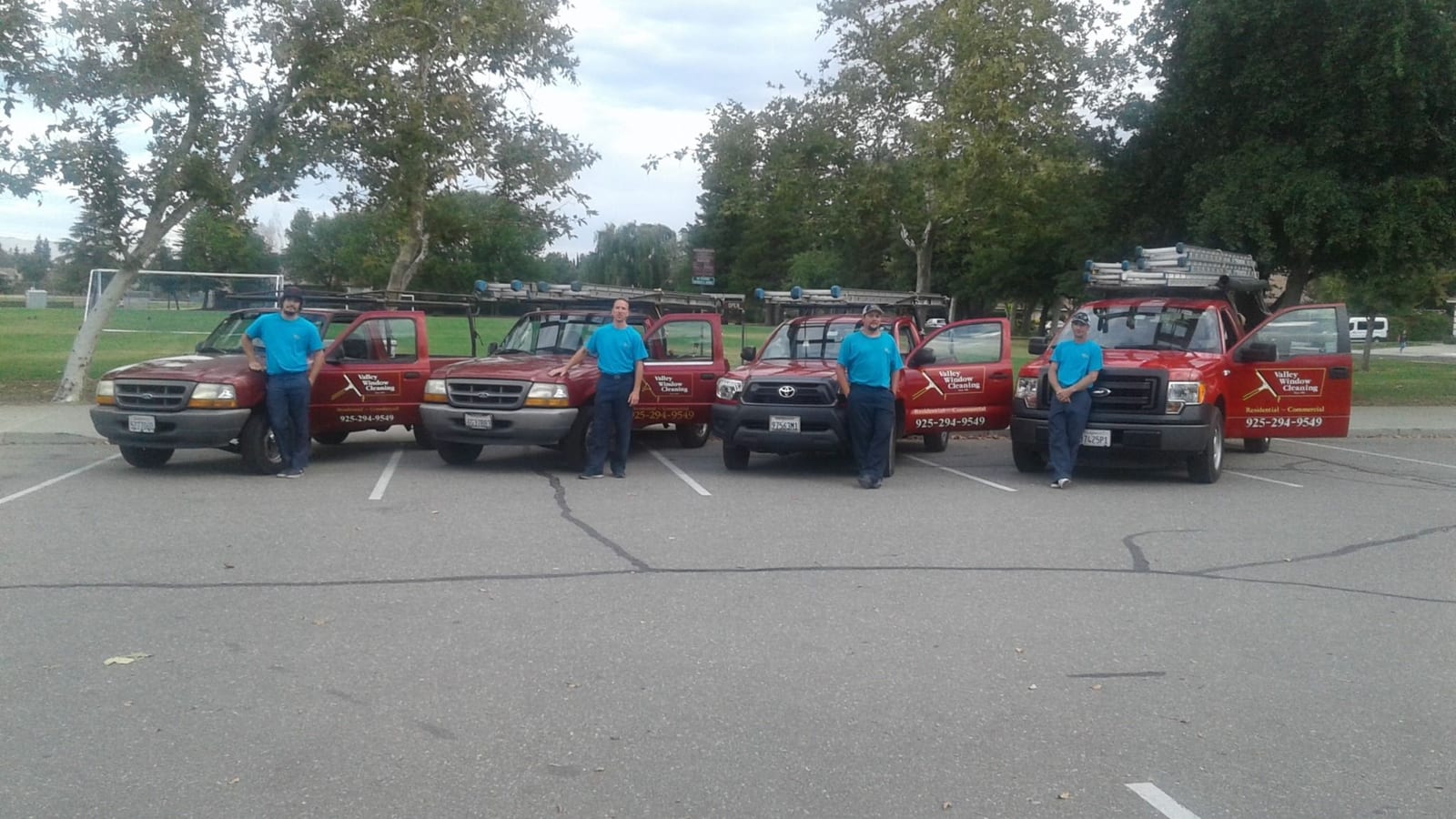Valley Window & Gutter Cleaning team standing beside their company service trucks