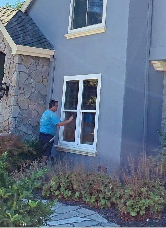 Technician cleaning an exterior window of a two-story home
